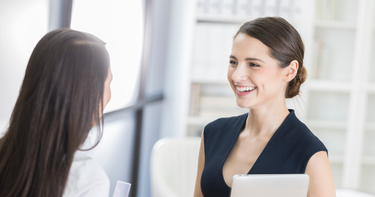 職場で笑顔で話す二人の女性